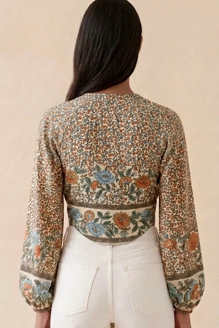 Person wearing a floral patterned top with long sleeves on a beige background