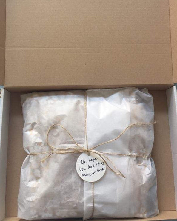 Cardboard box with a wrapped package on a floral-patterned surface