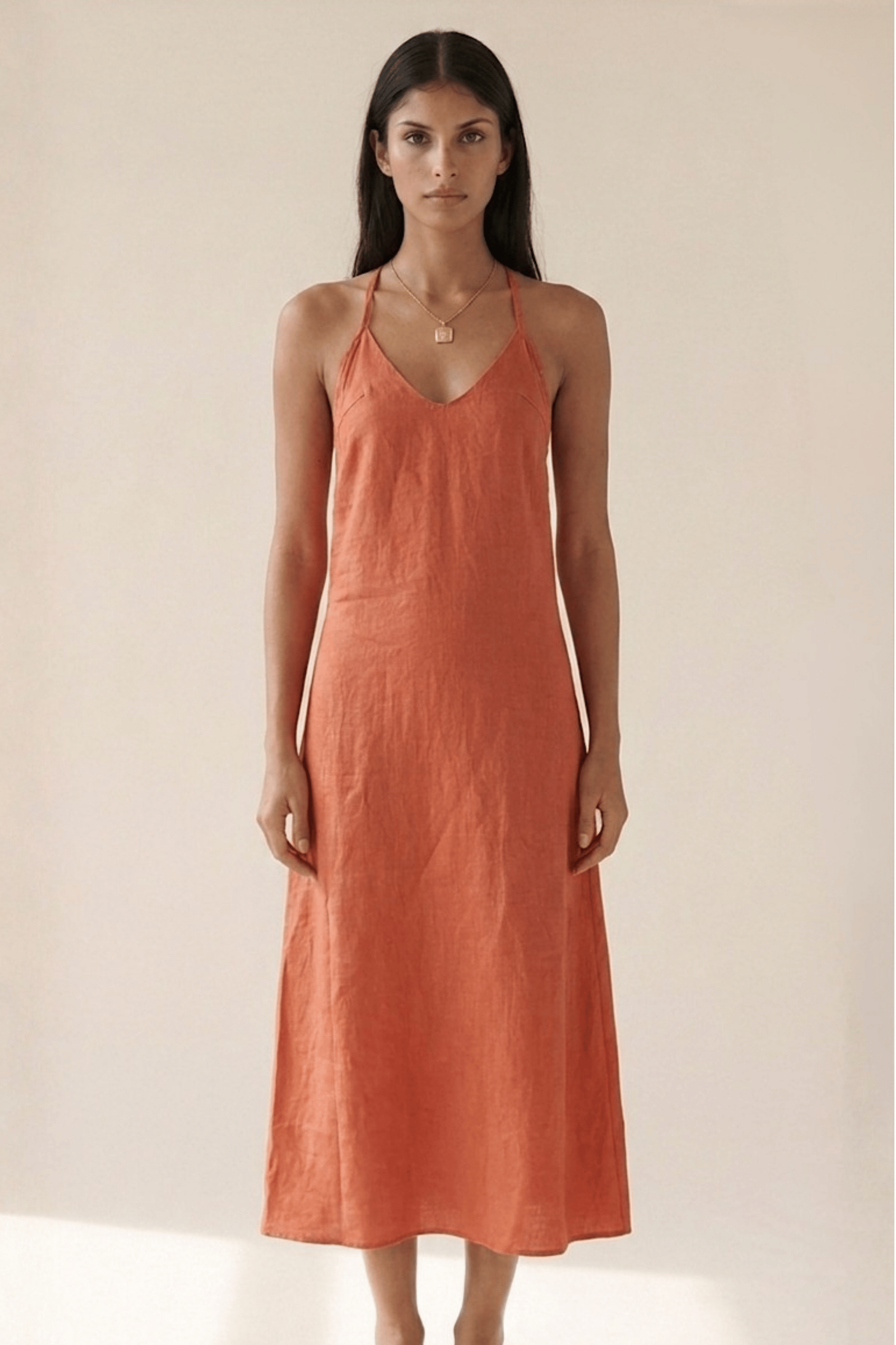 Woman wearing a rust-colored dress against a plain background