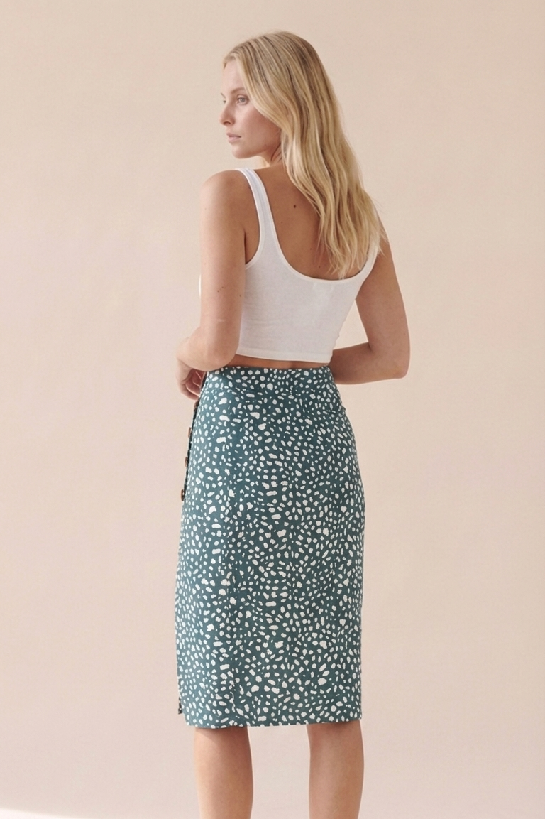 Woman wearing a white tank top and green floral skirt on a beige background